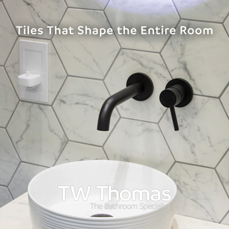 White marble-effect hexagon wall tiles behind a round countertop basin and matt black wall-mounted mixer, captioned Tiles That Shape the Entire Room
