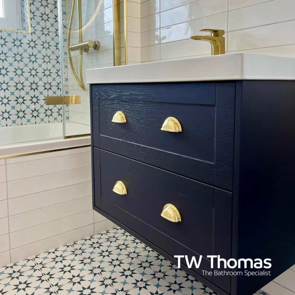 A navy wall-hung vanity with brass cup handles and a white countertop basin, against teal star-patterned wall and floor tiles
