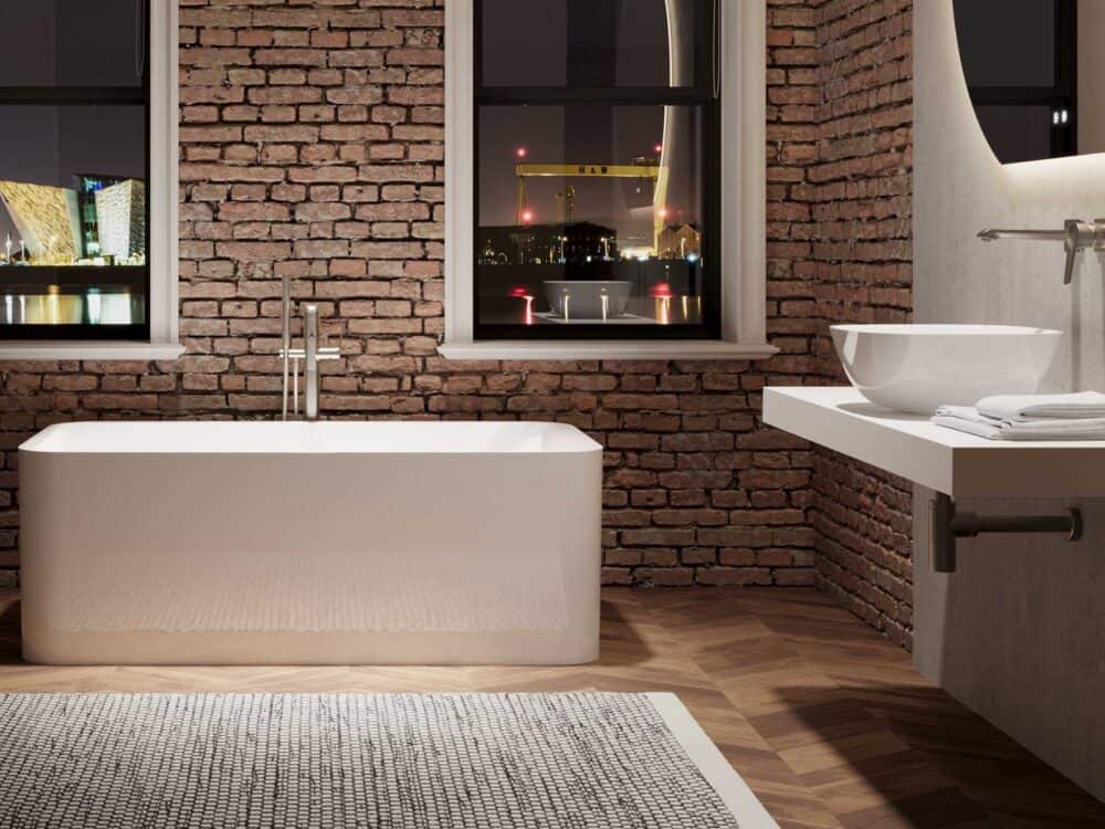 Adamsez rectangular freestanding bath in a loft bathroom with exposed brick and a stone basin shelf
