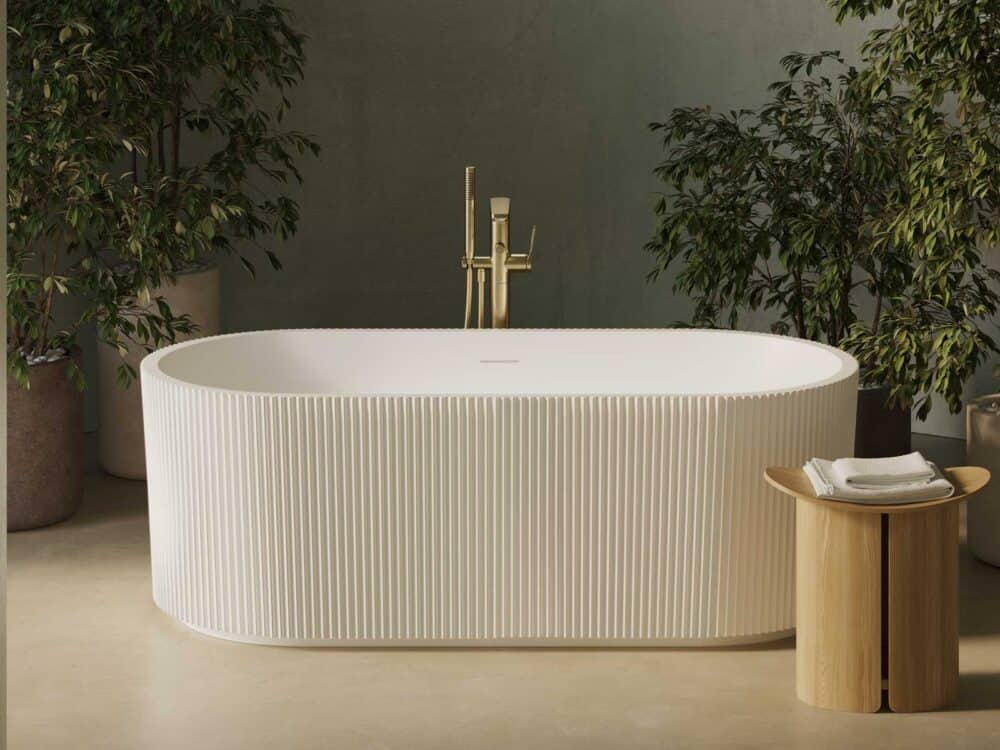 Adamsez fluted oval freestanding bath with a gold floor-standing tap against a soft green wall