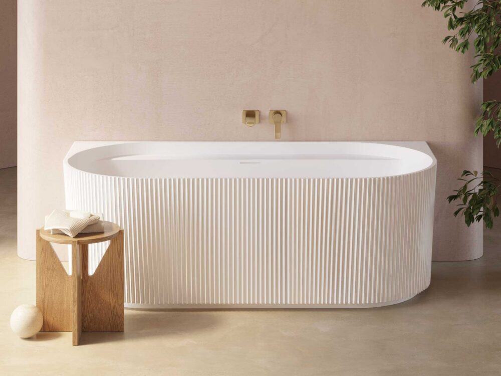 Adamsez fluted freestanding bath in a bright bathroom with a wooden stool and a long basin shelf