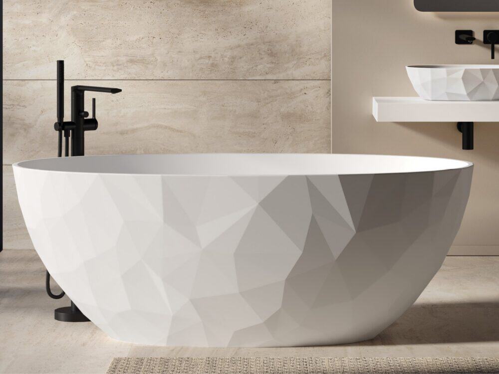 Adamsez Geo faceted freestanding bath beside a wall-hung basin shelf with matt black brassware