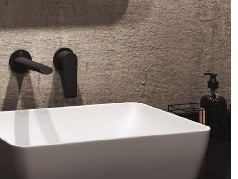 Aqualla matt black wall-mounted basin mixer above a white countertop basin on a textured wall