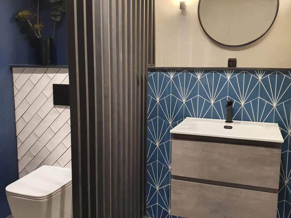 Armera Opa concrete grey vanity unit with a round mirror and Anthem wall-hung WC against patterned blue tiles