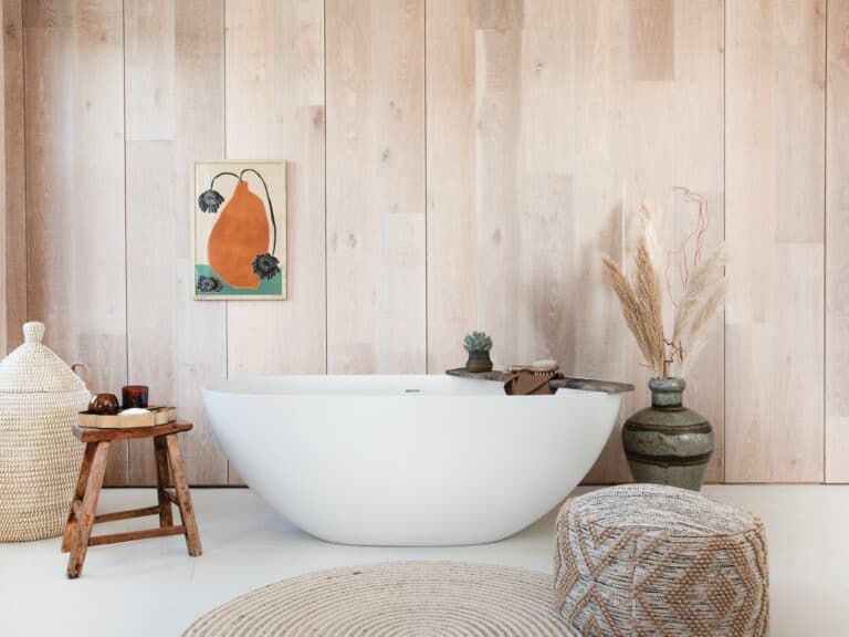 White freestanding bath in a bright room with timber-clad walls