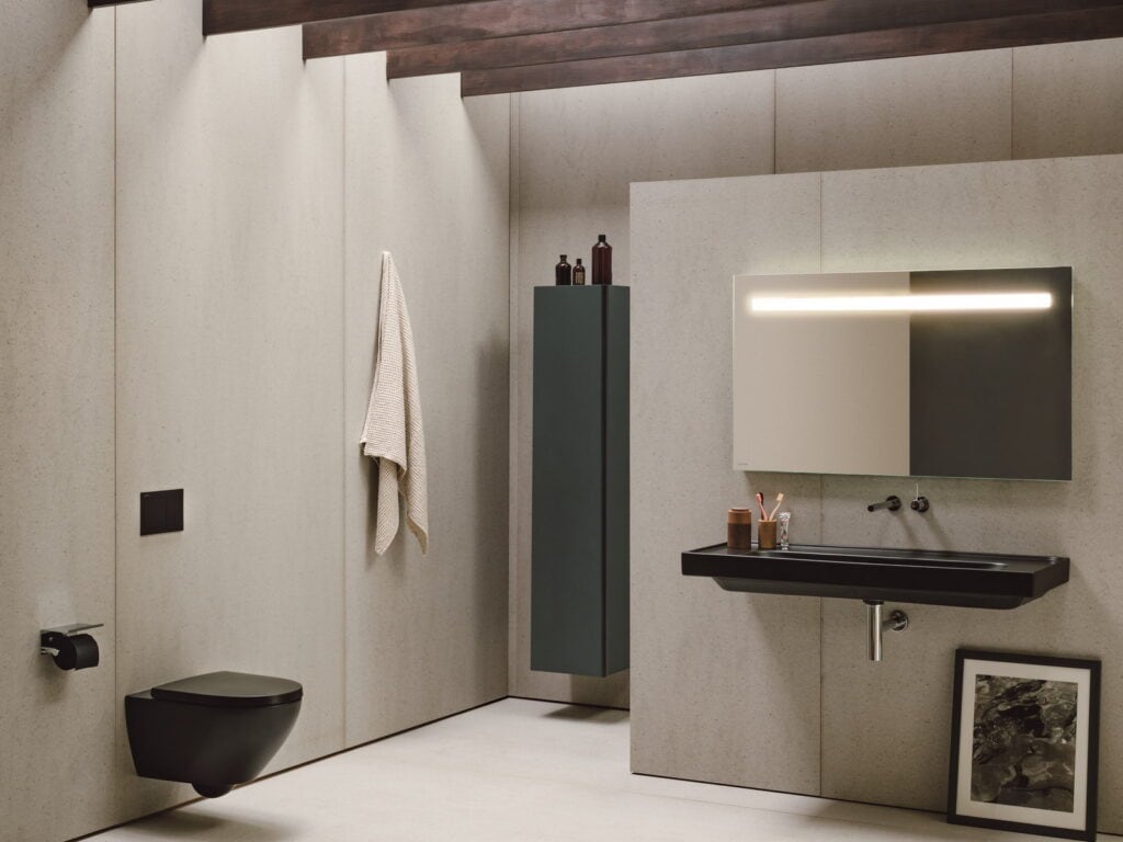 Laufen MEDA matt black washbasin and wall-hung WC in a stone-clad bathroom with dark timber beams and an illuminated mirror