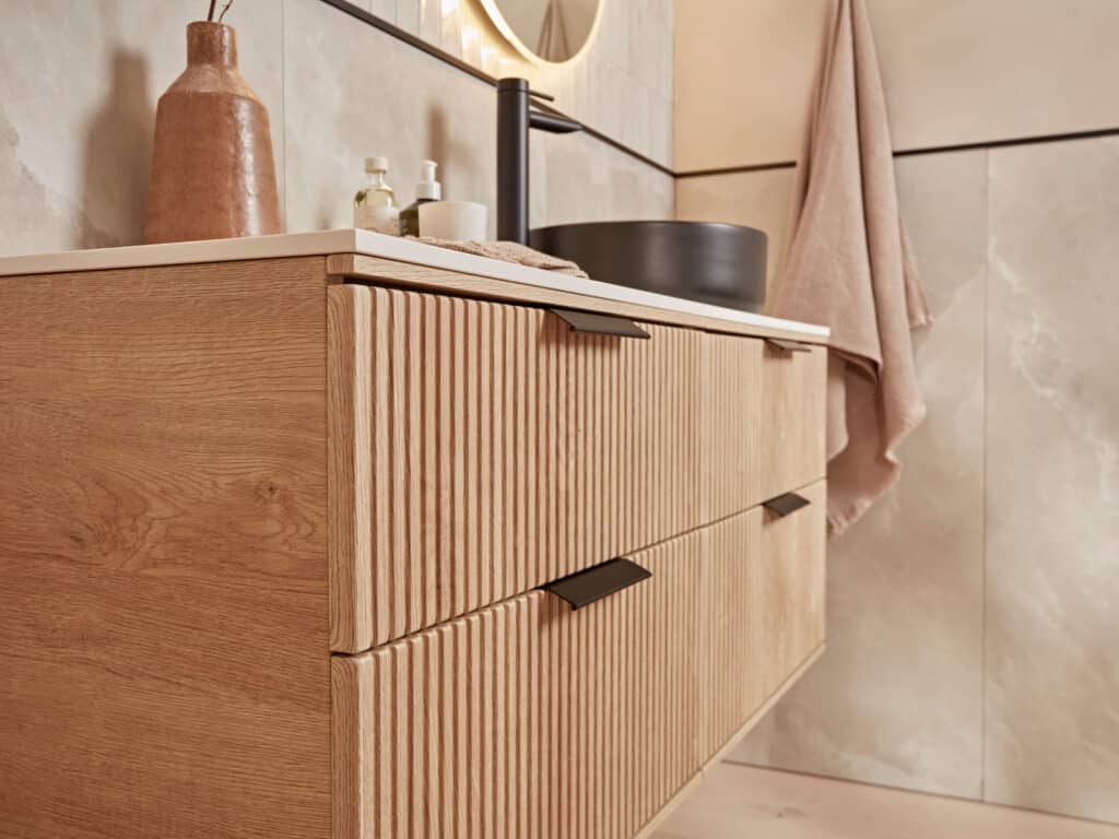 Close detail of a Roper Rhodes Scheme fluted vanity unit in sand oak beneath a stone worktop