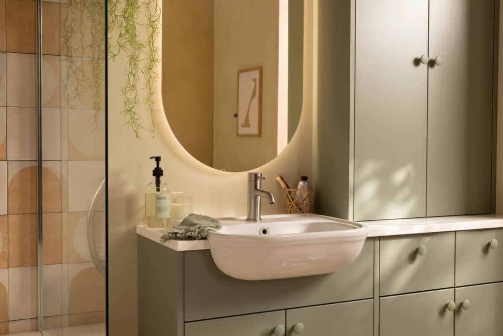 An R2 Muse fitted furniture run in aloe green with a semi-recessed basin and an illuminated oval mirror
