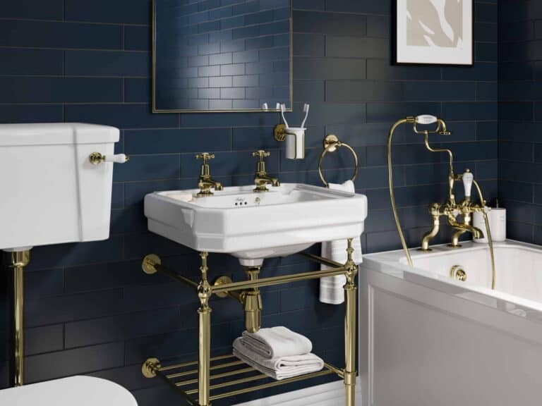Burlington basin on a gold washstand with a low-level WC and bath against navy metro tiles