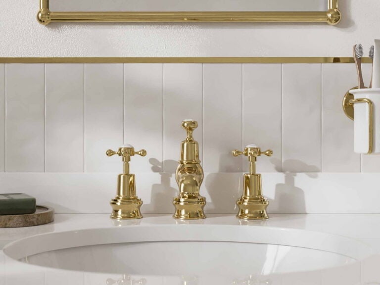 Burlington three-hole basin taps in gold with crosshead handles on a white basin