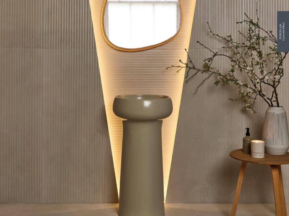 A fluted tiled wall behind a sculptural pedestal basin