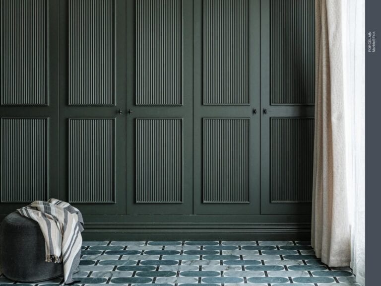 A teal patterned porcelain floor against dark green panelling