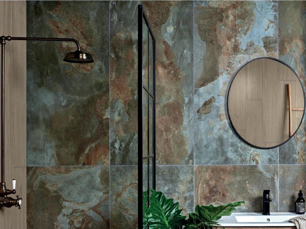A dark patterned porcelain shower wall with a round mirror