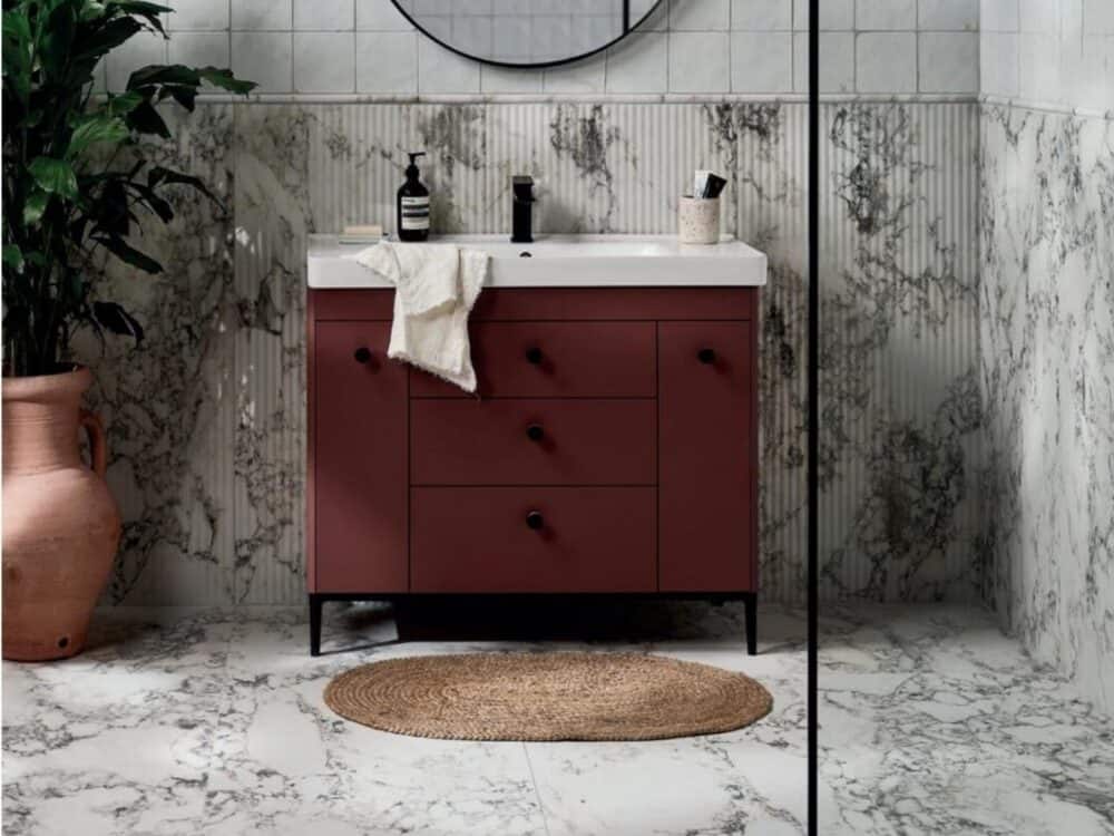 A marble effect wall behind a deep red vanity unit