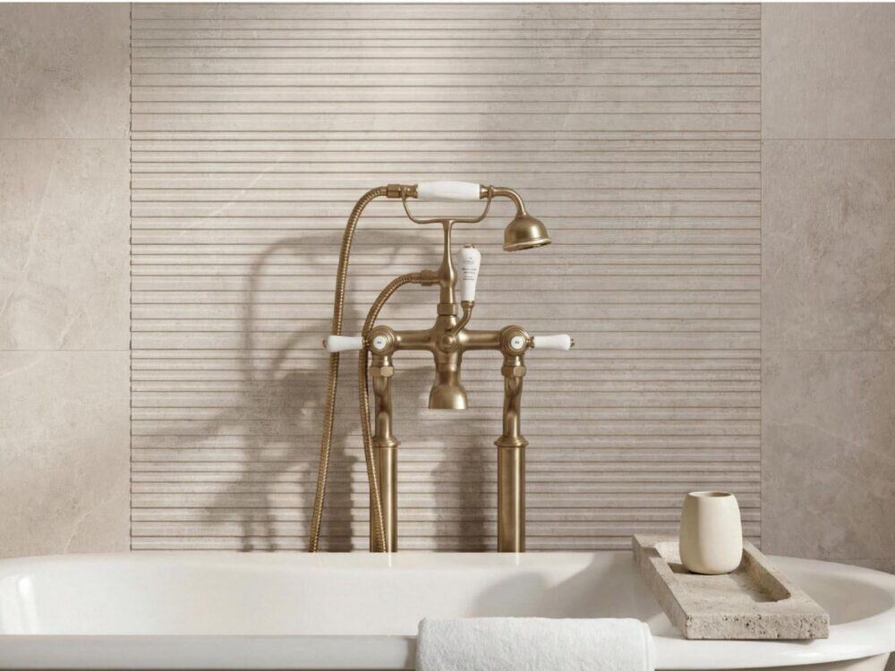 A ribbed cream tiled wall behind a roll top bath