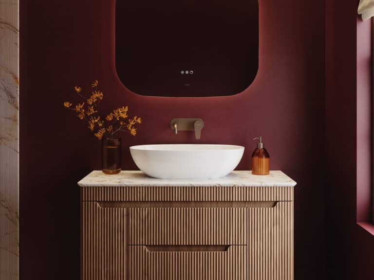 Calypso white oval countertop basin on a marble-effect top over a fluted walnut vanity, with a brushed gold wall-mounted mixer