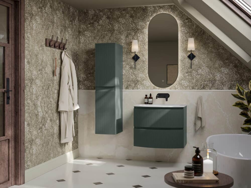 Calypso Levanto fluted wall-hung vanity and tall unit in fir green with a backlit oval mirror and freestanding bath