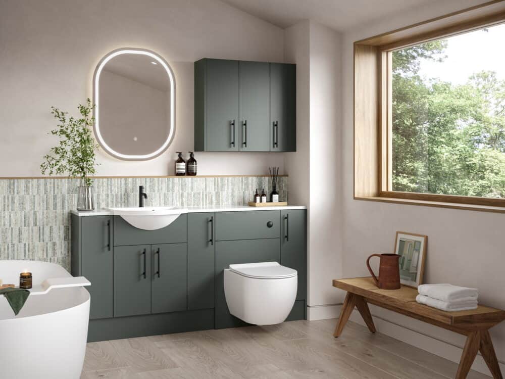 Calypso Cheviot fitted furniture in hunter green with a wall-hung WC, backlit oval mirror and freestanding bath