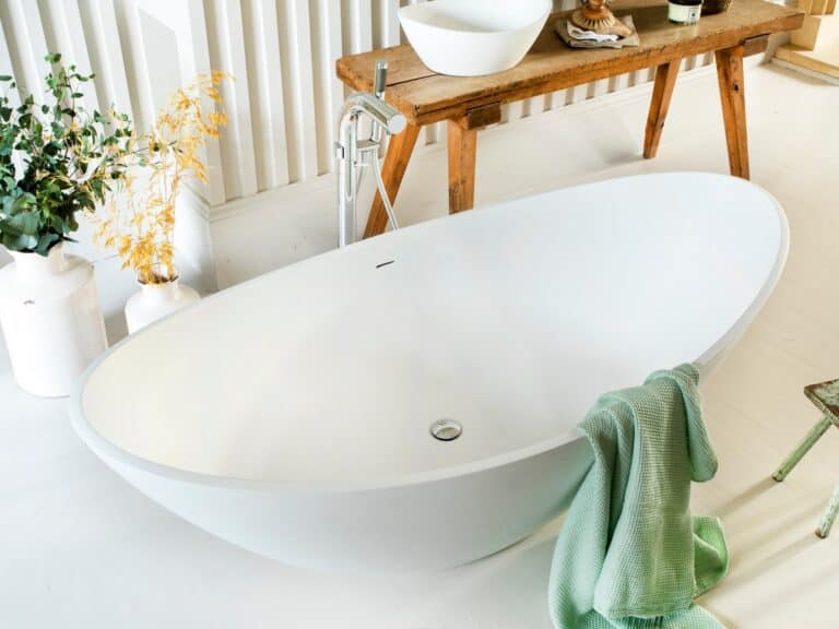 Freestanding bath with floor-standing tap and a green towel