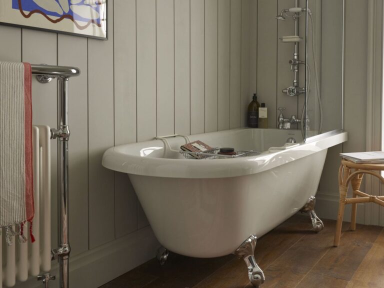 Chrome heated towel rail beside a Heritage roll-top bath