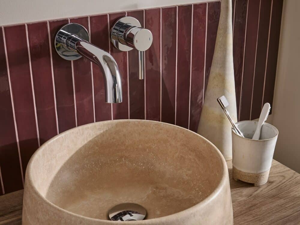 hib.inspire Nuvia natural stone countertop basin in Travertine against deep red tiles