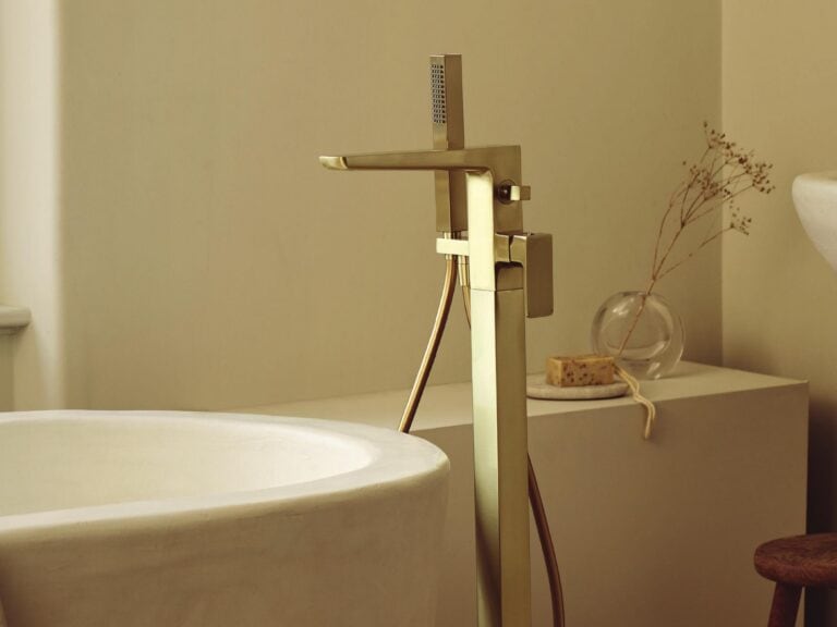 HiB floor-standing bath filler in brushed brass beside a freestanding bath