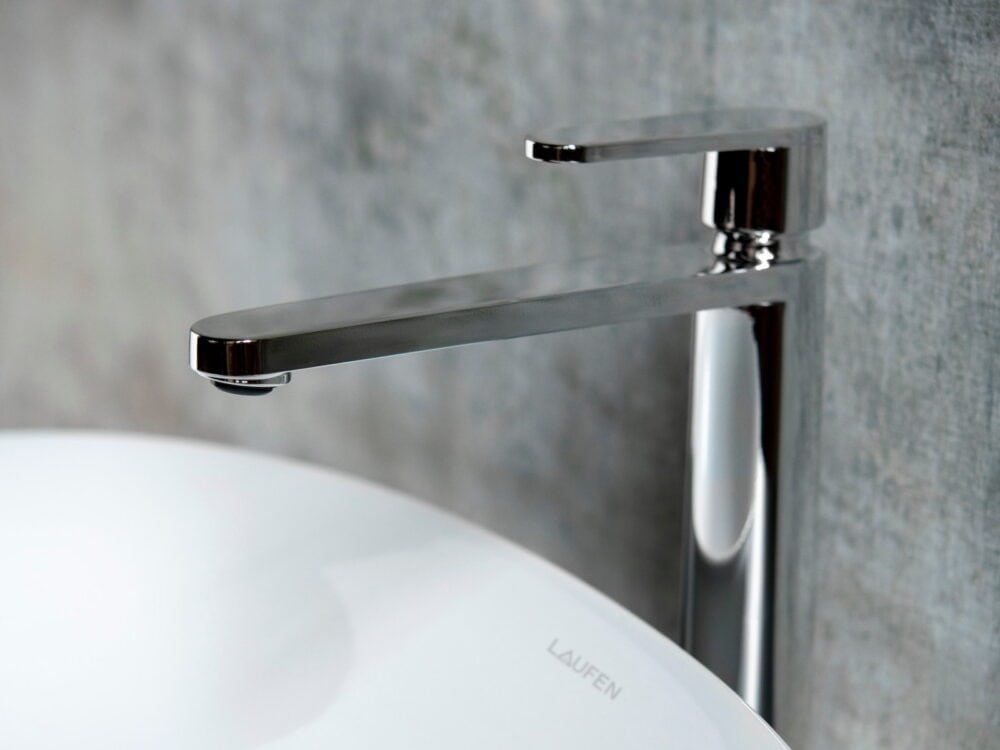 Laufen The New Classic tall chrome basin mixer over a round countertop washbasin