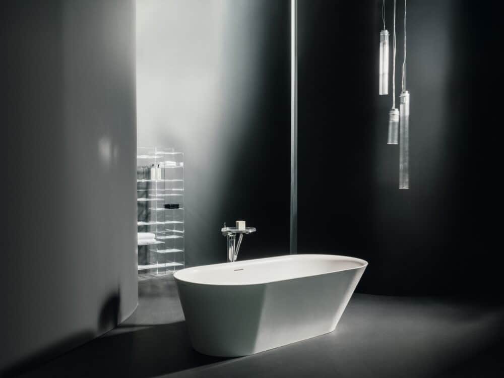 Kartell by Laufen freestanding bath with glass pendant lights in a dark bathroom