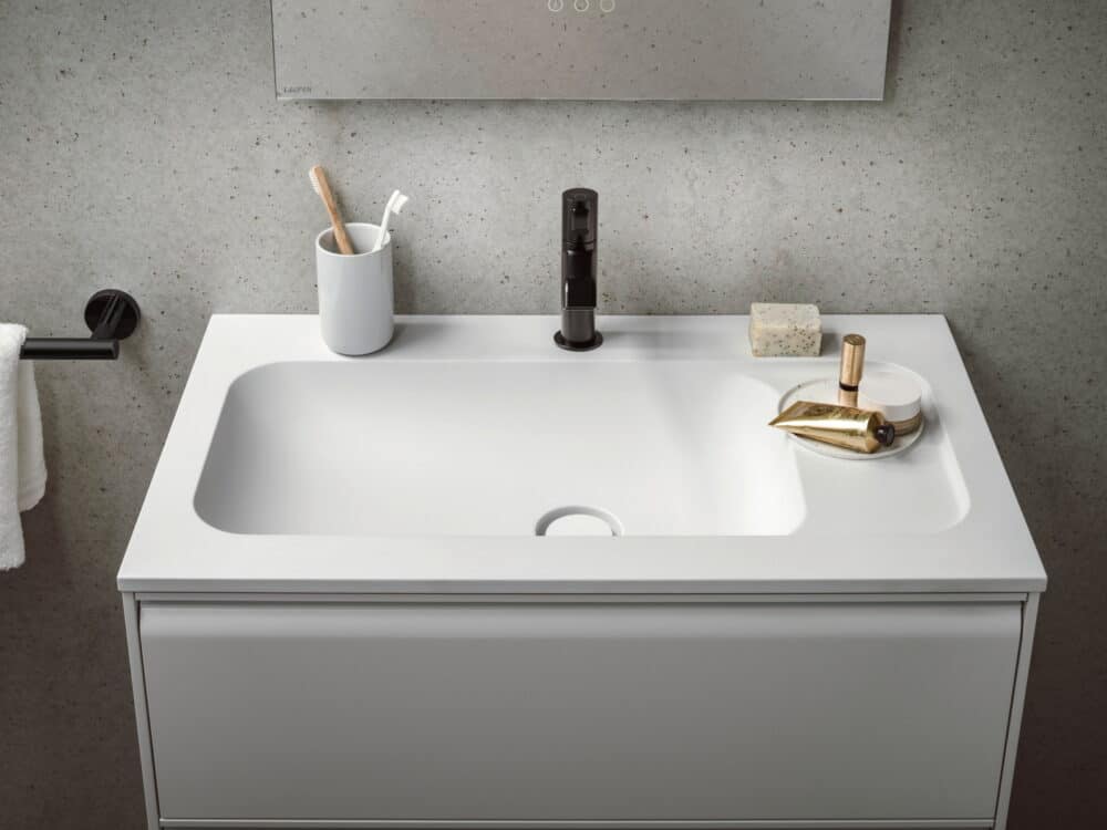 Laufen MEDA washbasin and vanity unit with a matt black basin mixer against a speckled concrete wall