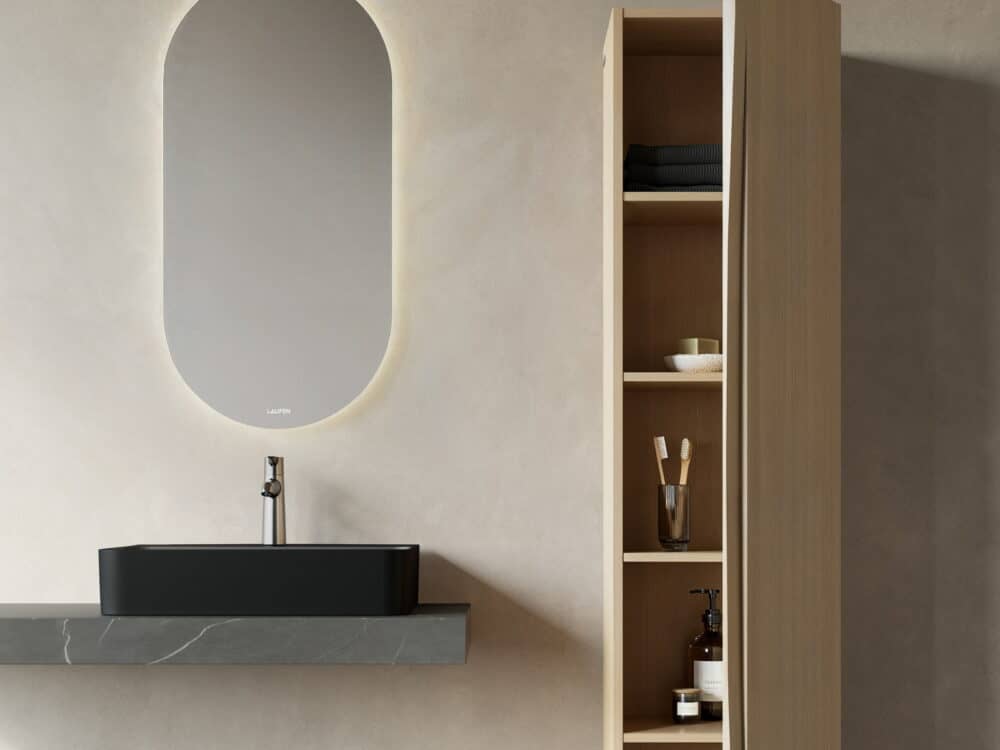 Laufen ARUN black countertop washbasin on a stone shelf below an oval backlit mirror, beside an open oak shelf unit