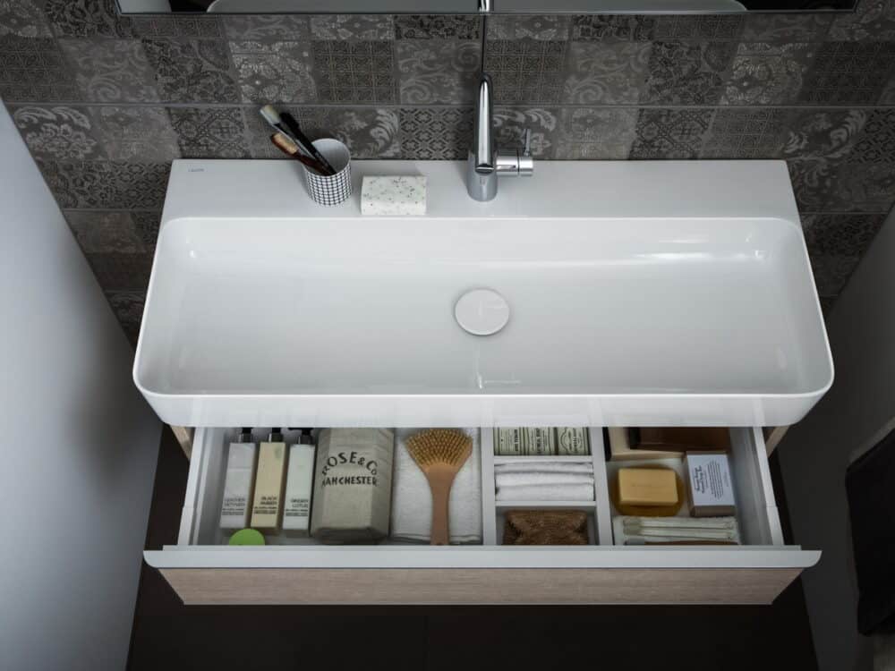 Laufen VAL washbasin with an open vanity drawer and a chrome mixer against patterned tiles