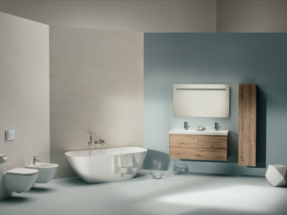 Laufen LUA freestanding bath, oak vanity unit, tall cabinet and wall-hung bidet in a pale blue bathroom
