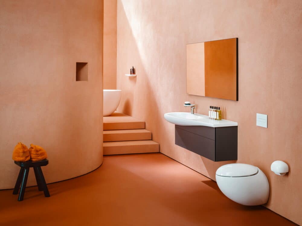 Laufen ILBAGNOALESSI egg-shaped wall-hung WC and washbasin on a dark vanity unit in a curved terracotta-rendered bathroom