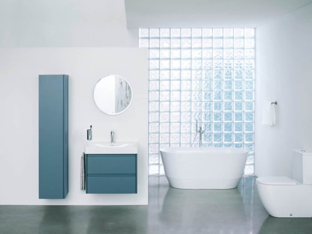 Laufen Pro X bathroom with Base 2.0 teal furniture, a freestanding bath and a glass-block wall