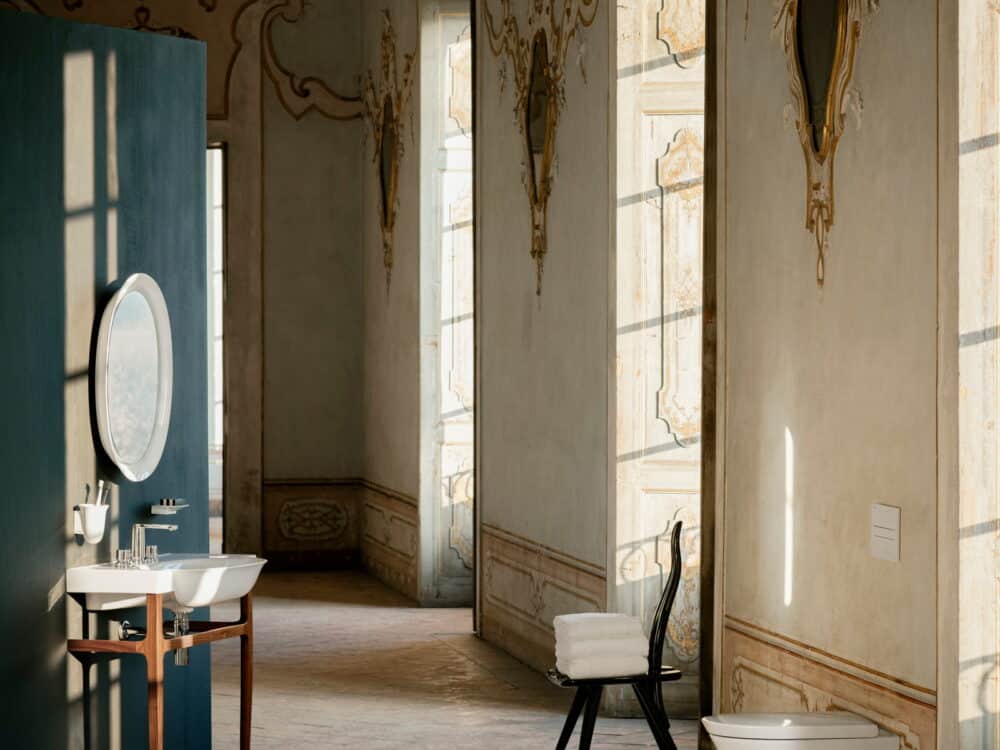 Laufen The New Classic washbasin on a walnut console stand below an oval ceramic-framed mirror in a frescoed palazzo room