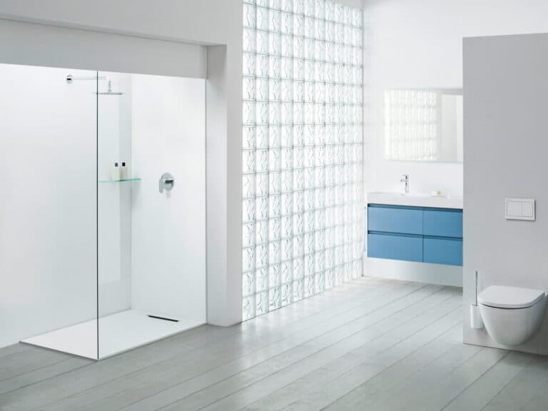 Laufen walk-in shower enclosure with a glass panel and a level-access tray beside a glass-block wall