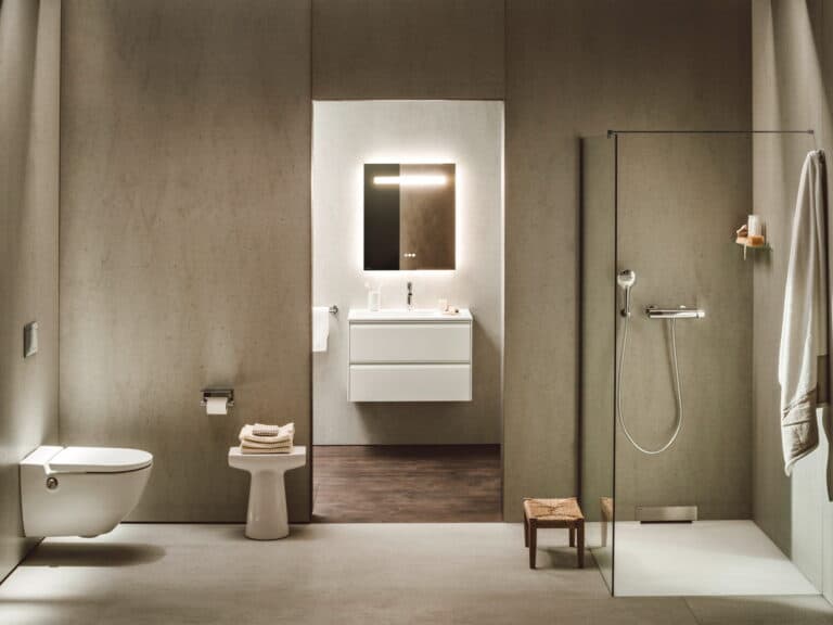 Laufen MEDA wet room with a level-access shower tray, glass screen, wall-hung WC and illuminated mirror in a concrete-walled bathroom