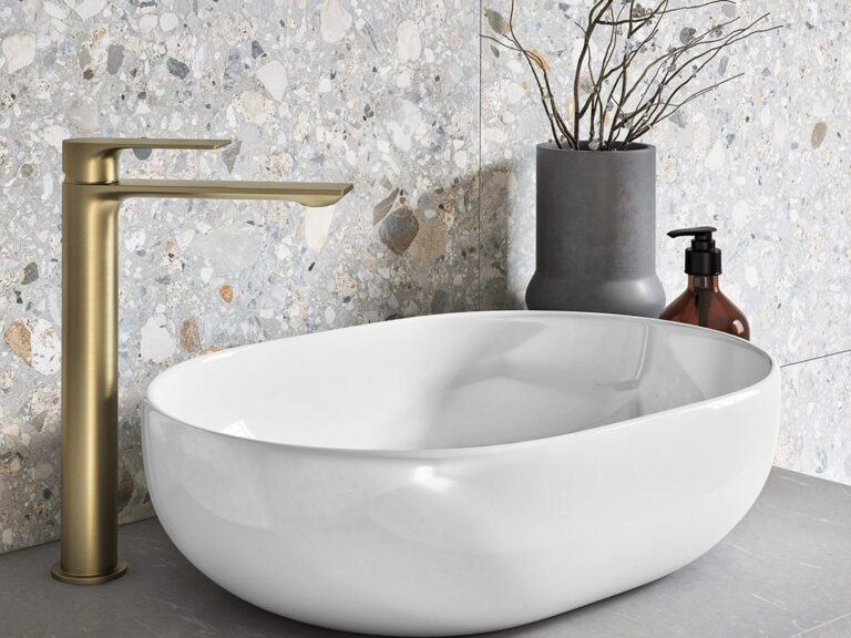 MyLife Nero oval countertop basin with a tall brushed brass mixer on a terrazzo-tiled vanity