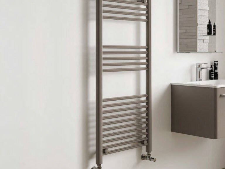 Phoenix chrome ladder heated towel rail on a white wall beside a wall-hung vanity unit and mirror