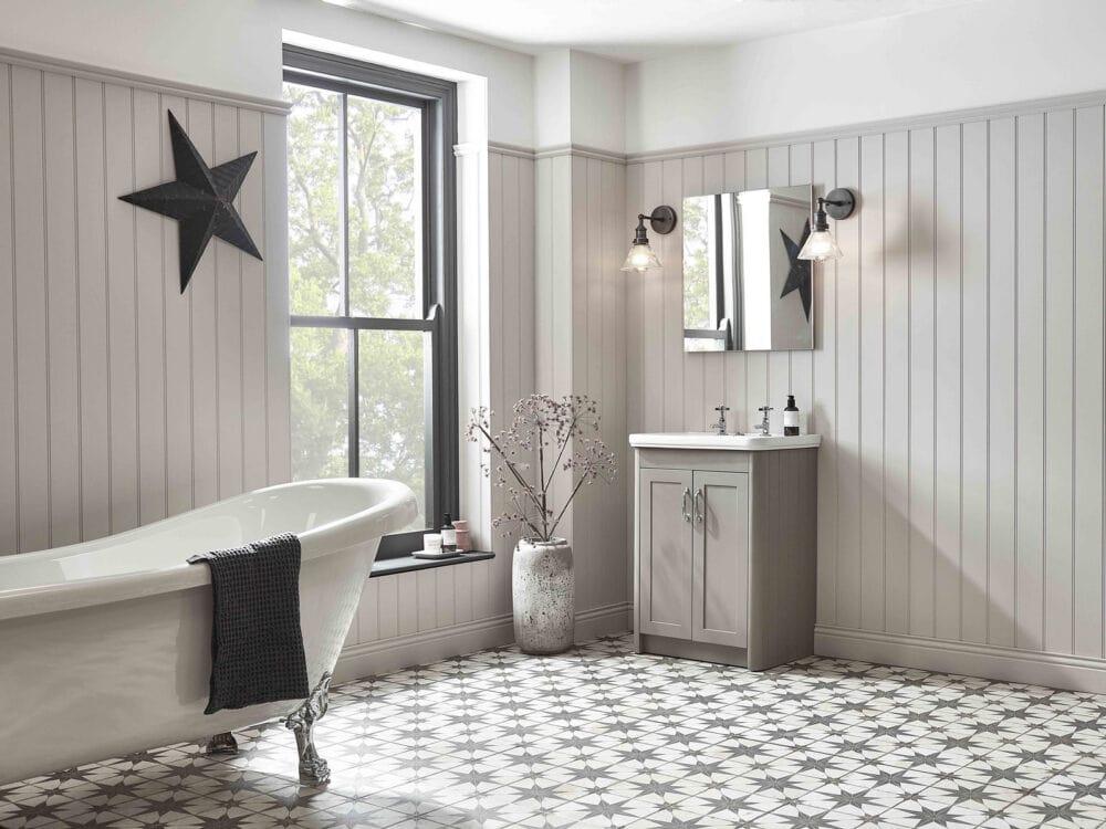 An R2 Halcyon freestanding vanity unit in stone grey in a panelled bathroom with a roll top bath