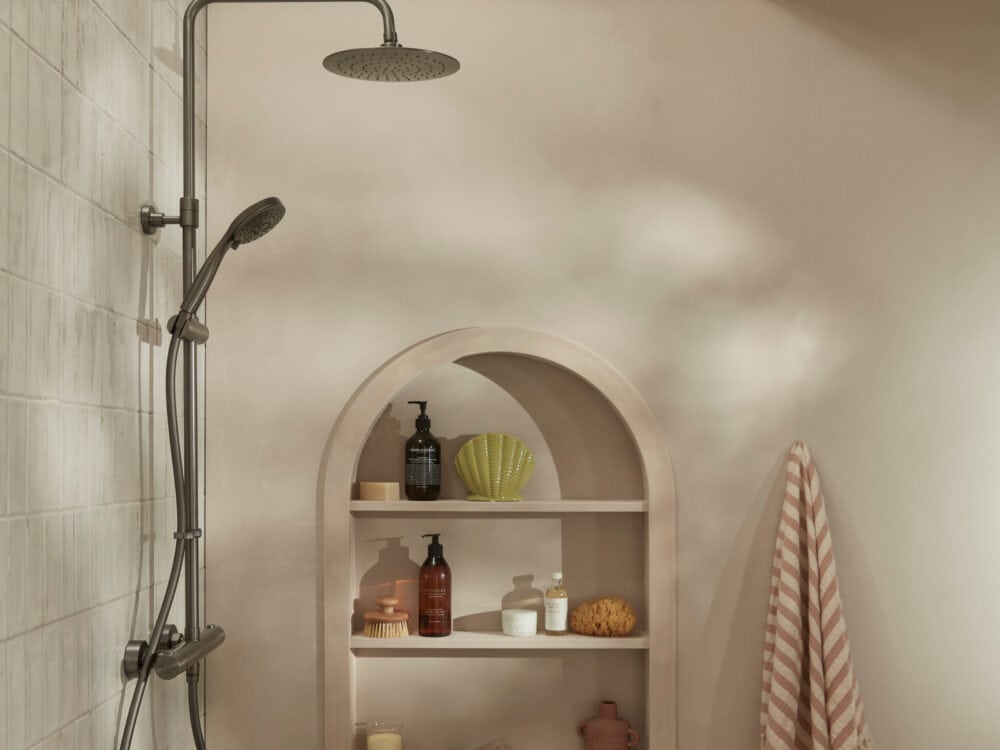 An R2 Marine bar shower in gunmetal against a plaster wall with an arched display niche
