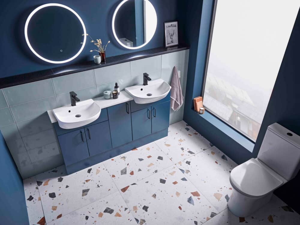 An R2 Muse fitted furniture run in dark blue with twin basins, two round illuminated mirrors and a terrazzo floor
