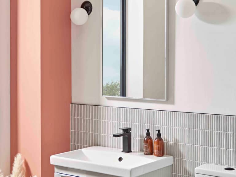 An R2 Framed plain wall mirror between two opal globe wall lights above a basin and fluted tiles
