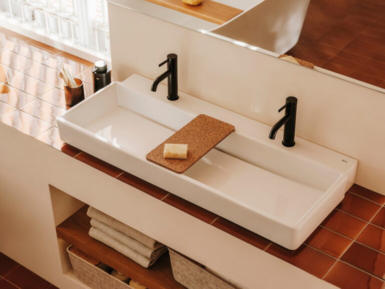 Roca Tura white countertop washbasins with matt black mixers on a plaster shelf above terracotta tiles
