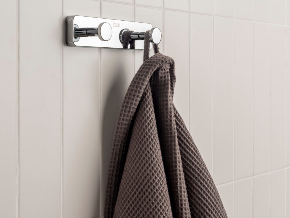 Roca Sonata chrome double robe hook with a waffle towel on white tiles