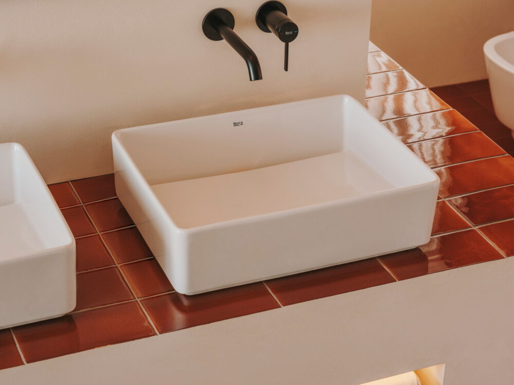 Roca Tura white countertop washbasin with matt black wall mixers on a terracotta-tiled surround