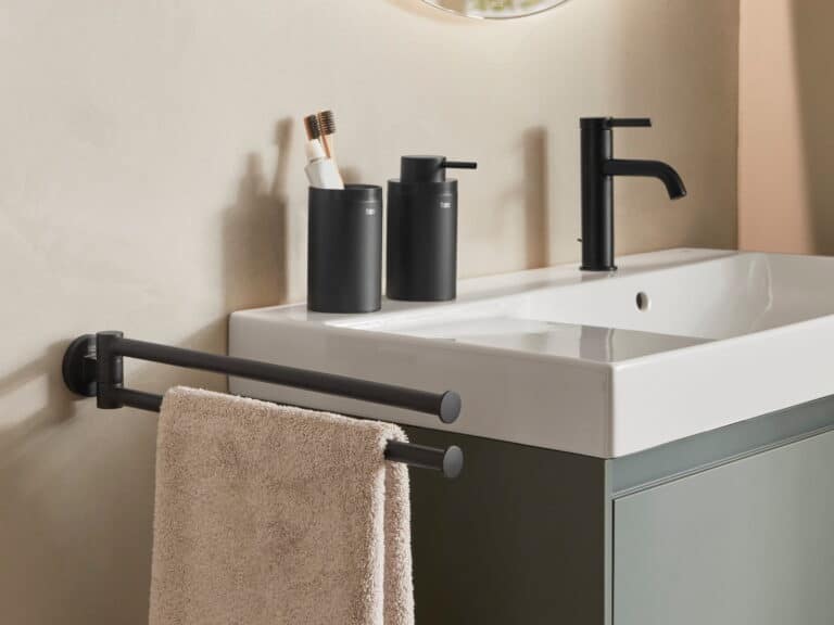 Roca Hotels Round matt black towel rail, soap dispenser and tumbler beside a washbasin on a sage vanity unit