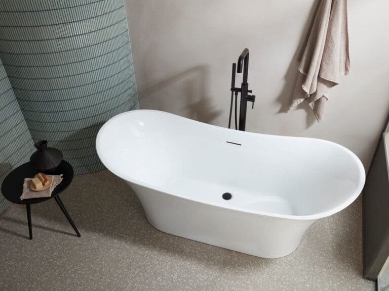 A Roper Rhodes Paradigm double ended freestanding bath with a black floor standing tap against a ribbed wall