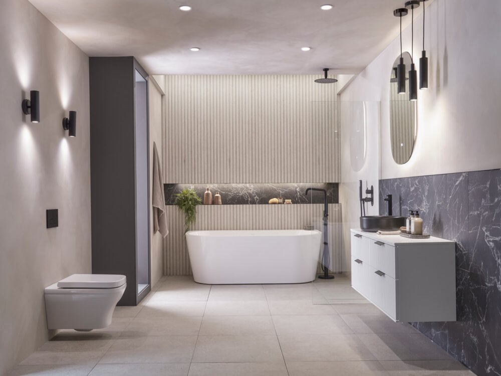 A Roper Rhodes bathroom lit by pendants, wall lights and an illuminated mirror together