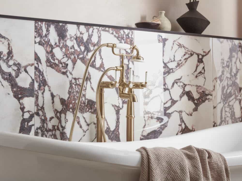 Brushed brass Roper Rhodes floor standing bath tap against a calacatta viola marble wall